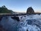 Fast streaming ocean water in front ot a rock hill at Watu Lumbung beach