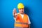 Fat asian workman wearing orange safety vest and yellow helmet making stop gesture