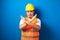 Fat asian workman wearing orange safety vest and yellow helmet making stop gesture