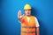 Fat asian workman wearing orange safety vest and yellow helmet making stop gesture