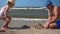 Fat father with hat and little playful daughter building castle from wet sand