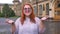 Fat ginger girl with glasses is walking in park under rain, raising hands, excited about rain, inspiration concept