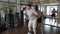 The fat man is doing physical exercises with a help of athlete, personal trainer for weight loss and body fitness in the