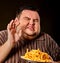 Fat man eating fast food french fries for overweight person.