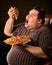 Fat man eating fast food slice pizza . Breakfast for overweight person.