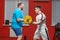 A fat man in the gym performs barbell lifting exercises at the limit of his powers under the guidance of a personal