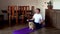 Fat man and pomeranian dog doing gymnastics at home on mat. Man in lotus position back sitting meditates dzen. Doing fitness with