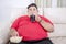 Fat man sipping a cola while grabbing popcorns