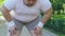 Fat man stops to restore breathing, jogging in park, struggle with overweight