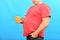 Fat obese man with a big belly holds a mug with a sweet drink in his hands