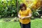 Fat overweight woman holding measuring tape around her waist while standing in the garden. Problems obesity female worried big