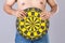 Fat people holding round yellow dartboard beside his belly position. Target of losing weight concept. Studio shot  on grey