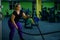 Fat woman doing strength training using battle ropes in the gym. The obese girl is engaged in circular exercises for