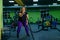 Fat woman doing strength training using battle ropes in the gym. The obese girl is engaged in circular exercises for