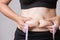 Fat woman hand holding excessive belly fat with measuring tape. Healthcare and woman diet lifestyle concept to reduce belly and