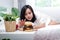 Fat woman lying on the bed Reaching for an empty hamburger on the table to eat on the bed.