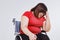 Fat woman sitting stressed in wheelchair on white background