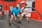 Fat young man is very concentrated performing battle rope exercise in the fitness gym under control of his personal