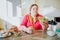 Fat young woman in kitchen sitting and eating food. Bowl with salad in hand. Plus size model look at it. Body positive