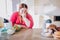 Fat young woman in kitchen sitting and eating food. Looking at sweets on right side. Salad and other healthy food on