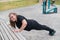 Fat young woman push up from the bench outdoors. A chubby smiling girl warms up before jogging. Sports for weight loss.