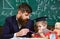 Father with beard, teacher teaches son, little boy. Individual schooling concept. Kid studies individually with teacher