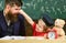 Father with beard, teacher teaches son, little boy, while little kid tweaks his nose. Teacher and pupil in mortarboard