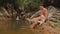 Father Blond Daughter Sit Play on Stony Bank with Waterfall