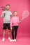 father and blonde daughter holding tennis rackets and ball, isolated