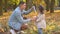 Father blowing air bubbles with little daughter in autumn park