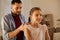 Father braiding daughter hair at home