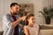 Father braiding daughter hair at home