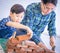 Father builder teaching his son to lay the brick wall for future career an