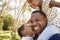 Father Carrying Children On Shoulders As They Walk In Park