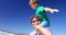 Father carrying son on his shoulders at beach