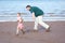 Father chasing daughter on muddy beach