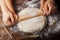 Father and child hands making the dough with flour, rolling pin and wheat ears on rustic wooden table top view.