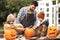 Father and children carving pumpkin for halloween in backyard