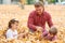 Father and children are lying on yellow leaves and having fun in autumn city park. They posing, smiling, playing. Bright yellow tr