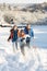 Father And Children Pulling Sledge Up Snowy Hill