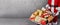 Father Christmas with a wheelbarrow full of colorful wrapped Xmas gifts in a panorama banner over grey concrete wall with copy