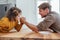 Father competing in arm wrestling with teen son, family spending time together.