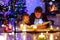 Father and cute little toddler boy reading book by chimney, candles and fireplace.