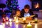 Father and cute little toddler boy reading book by chimney, candles and fireplace.