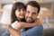 Father and daughter embracing sitting on couch looking at camera