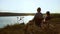 Father and daughter fishing on river bank at sunset