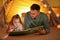 Father and daughter with flashlight reading book