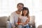 Father and daughter with gift box sitting on couch