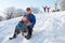 Father And Daughter Having Fun Sledging Down Hill