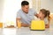 Father and daughter near modern toaster at kitchen table